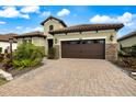 This home features a spacious brick-paved driveway leading to a two-car garage and well-maintained landscaping at 26833 Weiskopf Dr, Englewood, FL 34223