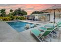 Relaxing poolside view featuring lounge chairs, manicured landscaping and a modern sunroom at 3228 Webber St, Sarasota, FL 34239