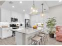 Bright kitchen featuring granite counters, stainless appliances, white cabinets, pendant lighting, and seating at the island at 383 Aruba Cir # 102, Bradenton, FL 34209