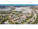 Aerial shot of condos nestled among green trees, a shopping center, and a pond under a blue sky at 4008 Crockers Lake Blvd # 13, Sarasota, FL 34238