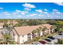 Tan two-story condo building showing landscaping and parking area on a sunny, tropical day at 4008 Crockers Lake Blvd # 13, Sarasota, FL 34238