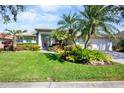 Beautiful single-story home with lush landscaping, mature palm trees, and a meticulously maintained lawn at 4941 Sabal Lake Cir, Sarasota, FL 34238