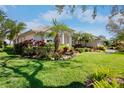 Charming single-story home featuring a beautifully landscaped front yard with tropical plants and lush green grass at 4941 Sabal Lake Cir, Sarasota, FL 34238