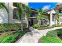 Condo exterior featuring a private entrance, screened lanai, lush landscaping, and a well-maintained walkway at 5710 Palmer Cir # 204, Lakewood Ranch, FL 34211