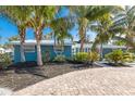 Charming blue home with lush landscaping and circular brick paver driveway at 6201 Holmes Blvd, Holmes Beach, FL 34217