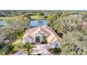 Stunning aerial view of home near lake featuring mature landscaping, tile roof, and brick paved driveway at 8116 Collingwood Ct, University Park, FL 34201