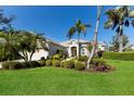 Landscaped front yard showcases a beige single-story home with tropical plants and bright green grass at 8803 18Th Nw Ave, Bradenton, FL 34209