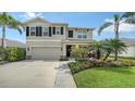 Two-story home featuring a manicured lawn, lush landscaping, and a two-car garage at 12716 Dusty Trail Dr, Sarasota, FL 34238