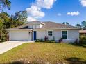 Charming single-story home featuring a two car garage, blue front door, and fresh landscaping at 2307 Homestead Cir, North Port, FL 34286