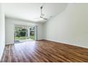 Bright living room features wood-look floors, a ceiling fan, and sliding glass doors to the backyard at 2307 Homestead Cir, North Port, FL 34286
