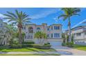 A two-story home with an arched entryway, a two-car garage, and beautifully manicured landscaping at 3491 Bayou Sound, Longboat Key, FL 34228