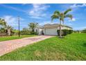 Lovely one-story home featuring lush landscaping, a two-car garage, and a brick driveway under blue skies at 3631 Pebble Ter, Punta Gorda, FL 33980