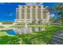 Front view of an elegant condo building overlooking a serene pond with a fountain and manicured lawn at 501 Haben Blvd # 204, Palmetto, FL 34221