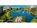 Aerial view of the waterfront complex with access to the beach with lake, fountain and tiki hut areas at 5780 Midnight Pass Rd # 210, Sarasota, FL 34242