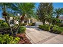 Inviting home showcasing lush landscaping, palm trees, and a driveway leading to the attached garage at 7015 Stanhope Pl, University Park, FL 34201