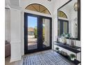 Stylish foyer featuring a black framed mirror, decor, patterned rug, and a view to the paver driveway at 7024 Brier Creek Ct, Lakewood Ranch, FL 34202