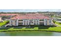 Exterior of condo building with neutral paint, red roof tiles, and pond view at 1005 Villagio Cir # 106, Sarasota, FL 34237
