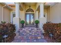 Elegant front entrance with brick steps, potted plants, and stately pillars framing the arched doorway and double doors at 12622 Safe Harbour Dr, Cortez, FL 34215