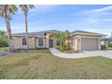 Beige single Gathering home exterior features a two-car garage, manicured landscaping, and palm trees at 2260 Island Creek Rd, Sarasota, FL 34240