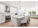 Bright, all-white kitchen with stainless steel appliances, island with bar seating, and hardwood flooring at 3319 S Osprey Ave, Sarasota, FL 34239