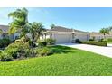 Charming home featuring a well-manicured lawn, colorful flowerbeds, and a convenient two-car garage at 5283 Chase Oaks Dr, Sarasota, FL 34241