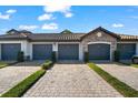 Attached garages featuring a paved driveway, neat landscaping, and stone detailing at 5537 Palmer Cir # 205, Lakewood Ranch, FL 34211