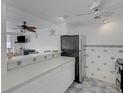 Kitchen open to living space with white cabinets and stainless steel refrigerator at 7000 Beach Plz # 905, St Pete Beach, FL 33706