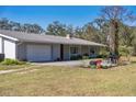 Home exterior showcasing an attached garage, brick chimney, and an outdoor patio area with a grill and table at 1510 Lena Ln, Sarasota, FL 34240
