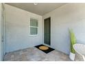 Cozy covered porch with tiled flooring, green front door and a view of the landscaped outdoors at 264 Van Gogh Cv, Bradenton, FL 34212