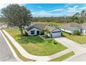 Aerial view of a home featuring a well-kept lawn, a pond in the back, and mature landscaping at 279 Park Forest Blvd, Englewood, FL 34223