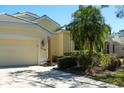 A well-maintained home exterior featuring manicured bushes, palm trees, and a lush green lawn for a serene setting at 3116 Woodland Fern Dr, Parrish, FL 34219