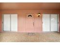 Covered front porch with a pink painted front door and two sliding glass doors at 441 Rubens E Dr, Nokomis, FL 34275
