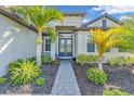 Inviting entryway with brick walkway leads to double doors with decorative wreath accents and tropical landscaping at 4813 Sparkling Sea Ln, Lakewood Ranch, FL 34211