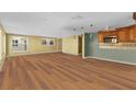 Open concept living room and kitchen with wood floors, yellow and green walls, and lots of sunlight at 6140 Midnight Pass Rd # A10, Sarasota, FL 34242