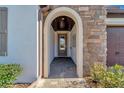 Arched entrance features a stone wall, tiled floor, and a glimpse of the front door with glass inserts at 12026 Perennial Pl, Bradenton, FL 34211