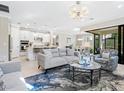 Open-concept layout with gray sofa, tile floors, and ample natural light, flowing to a modern kitchen at 12404 Golden Sage Dr, Sarasota, FL 34238