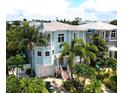 Charming light blue two-story home with garage, balconies, white trim, and lush tropical landscaping at 130 50Th St, Holmes Beach, FL 34217