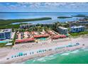 Gorgeous aerial view of beachfront condos with private pool and beach access, complete with blue umbrellas on white sand at 4621 Gulf Of Mexico Dr # 19B, Longboat Key, FL 34228