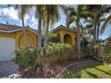 Yellow house with an arched doorway and several palm trees at 5007 Palermo Dr, Punta Gorda, FL 33950