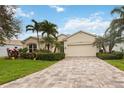 Charming single-story home featuring a paver driveway, lush landscaping, and a two-car garage at 5112 52Nd W Ave, Bradenton, FL 34210