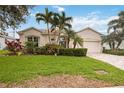 Charming home featuring a well-manicured lawn, a paved driveway, and lovely landscaping with palm trees at 5112 52Nd W Ave, Bradenton, FL 34210