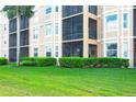 Exterior view of an apartment balcony featuring a screened-in porch and lush green landscaping around the building at 8403 Grand Estuary Trl # 103, Bradenton, FL 34212