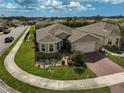 Aerial view of a single Gathering home showcasing its manicured lawn, brick driveway and landscaping at 9032 Excelsior Loop, Venice, FL 34293