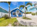 Charming blue home with tropical landscaping features a welcoming front door and ample parking space at 2408 Avenue B, Bradenton Beach, FL 34217