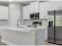 Kitchen boasts stainless steel appliances, quartz countertops, a kitchen island with breakfast bar, and white cabinets at 3 Boswell St, North Port, FL 34288