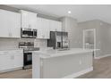 Bright kitchen features white cabinets, stainless steel appliances, quartz countertops, and island with breakfast bar at 3 Boswell St, North Port, FL 34288