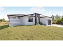 Modern home with a clean white exterior, black accents, and a well-maintained lawn under a sunny sky at 302 Liden St, Port Charlotte, FL 33953