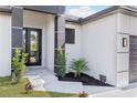 Close-up of the front entrance with a black door, modern lighting, and neatly arranged landscaping at 302 Liden St, Port Charlotte, FL 33953