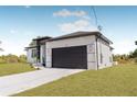 Side view of the home showcasing the dark garage door, white siding, and neatly trimmed lawn at 302 Liden St, Port Charlotte, FL 33953