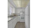 Galley kitchen featuring white appliances, cabinets, and neutral countertops at 3751 S School Ave # 9, Sarasota, FL 34239